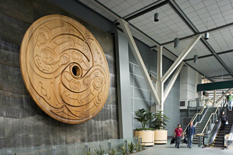 A large carved wooden art piece made by an indigenous Coastal Salish artist at the entrance of the Vancouver International Airport.