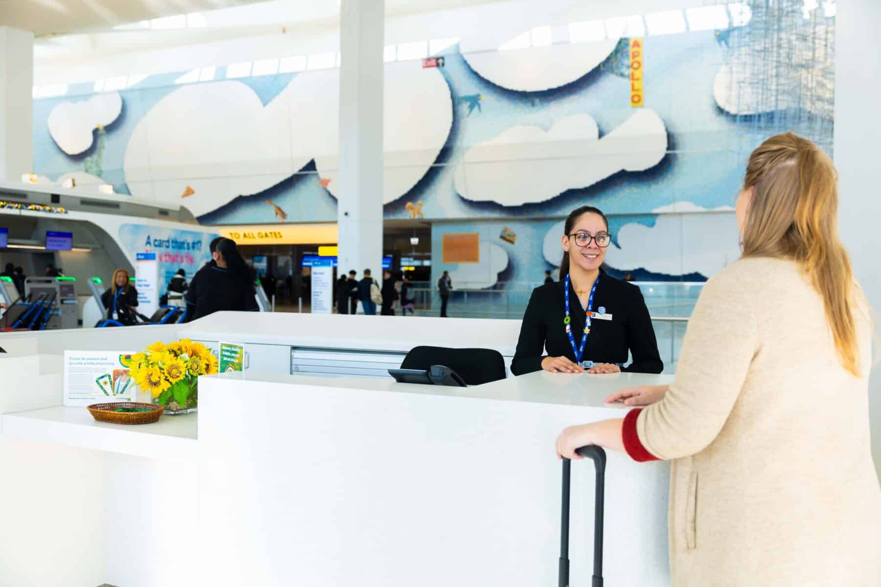 Check-in agent assisting passenger at airport terminal.